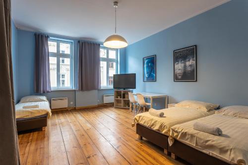 a bedroom with two beds and a desk with a tv at Apartamenty Kopernika in Toruń