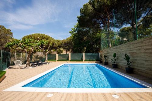 a swimming pool in a backyard with a wooden deck at Maravillosa casa con piscina grande y bosque in Tordera