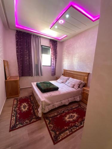 a bedroom with a bed with a pink lighting at Bouznika in Bouznika