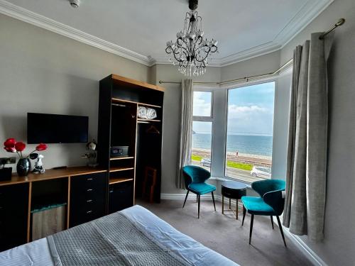 a bedroom with a bed and a desk and chairs at Hotel No5, Beachfront with Free Private Car Park in Llandudno