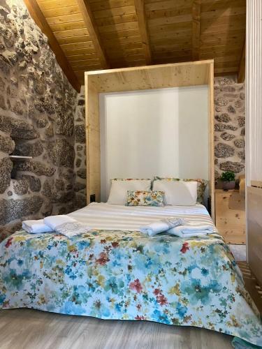 a large bed in a room with a stone wall at VillaGarcia-Casa da Marianinha in Terras de Bouro