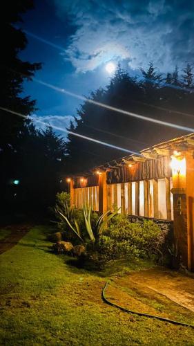 a fence in a yard at night with the moon at Rancho Cumbre Monarca in La Ciénega