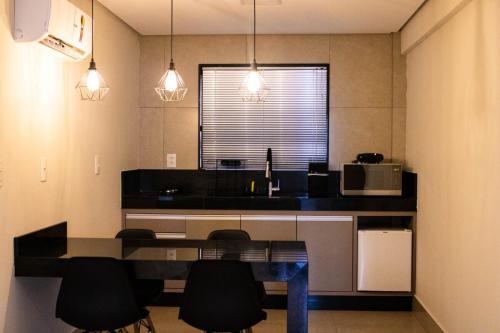 a kitchen with a table and chairs and a microwave at ESCARPAS FLATS in Capitólio
