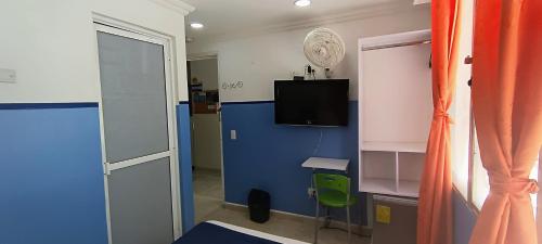 a room with a blue wall and a television at Casa Hotel Manco Mora in Medellín