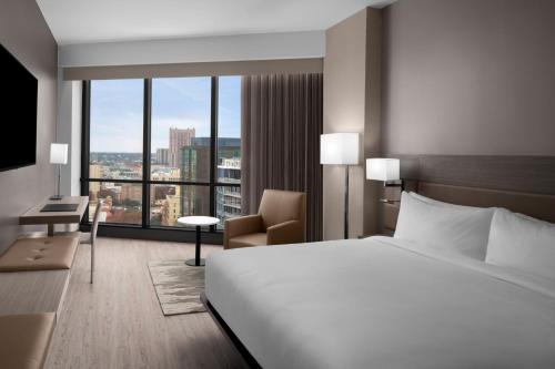 AC Hotel by Marriott San Antonio Riverwalk في سان انطونيو: غرفة فندقية بسرير ونافذة كبيرة