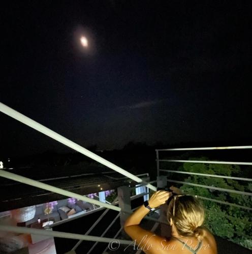 a woman taking a picture of the moon at night at Costa Nube in Caye Caulker