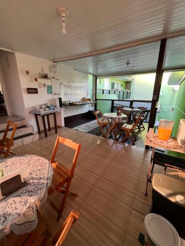 a room with tables and chairs and a kitchen at POUSADA ALEFER in Matinhos