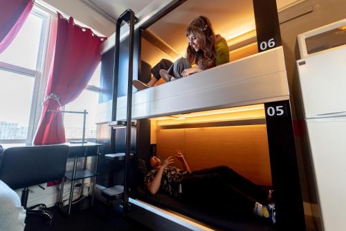 eine Frau auf einem Etagenbett in einem Zimmer in der Unterkunft Music City Hotel - Home of the San Francisco Music Hall of Fame in San Francisco