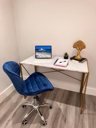 a desk with a blue chair and a laptop on it at Sea Breeze - Coast in Bournemouth