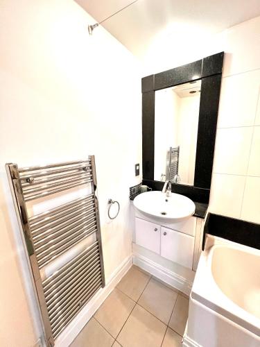 a bathroom with a sink and a toilet and a mirror at Super Modern 3-Bedroom Apartment in London