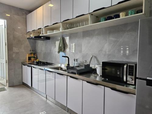a kitchen with white cabinets and a black microwave at Spacious 5-bedroom, 4-bath townhouse in Legazpi City in Legazpi