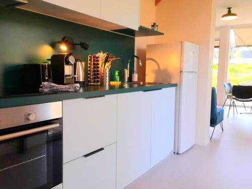 - une cuisine avec des placards blancs et un mur vert dans l'établissement L'îlot - Cosy moderne avec parking, à Bourges