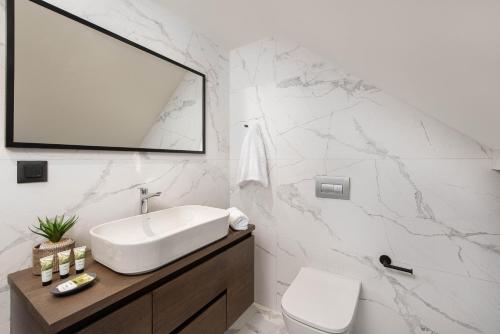 a white bathroom with a sink and a mirror at 30 Senses Luxury Apartment Insight in Ialyssos