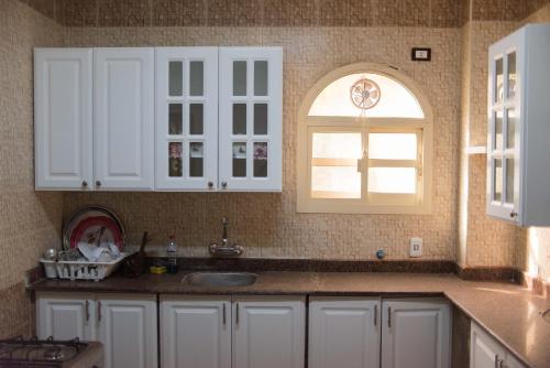 cocina con armarios blancos, fregadero y ventana en Zayed Villa with 4 apartments , Giza , 6 of October,Sheikh Zayed,Egypt شقق فلا الشيخ زايد en Sheikh Zayed