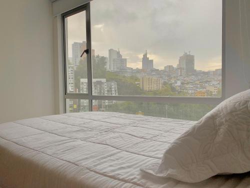 Cama blanca en habitación con ventana grande en Exclusivo Apartamento De Lujo cerca a cable plaza, en Manizales