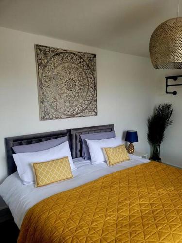 Un dormitorio con una cama grande con almohadas amarillas y blancas en No 1 The Terrace en Rainhull