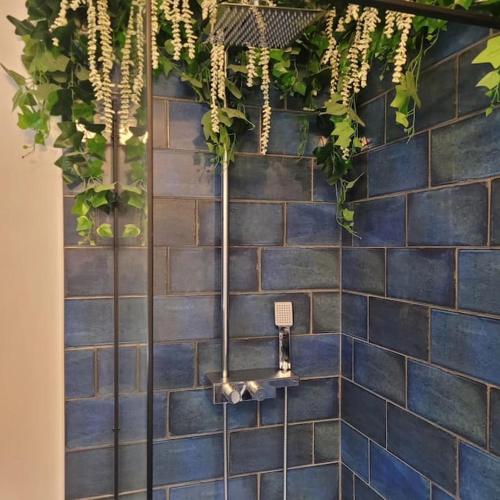 a bathroom with a blue tiled wall with plants at No 1 The Terrace in Rainhull