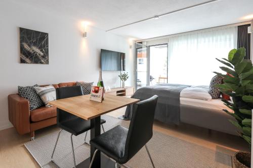 Un dormitorio con una cama y una mesa con una botella de vino en Spirit Apartments - Studio #3 - Balkon - Parkplatz, en Engelberg