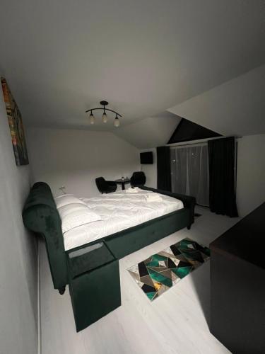 - une chambre avec un lit vert et une chaise dans l'établissement Apartamente 9, à Băile Felix