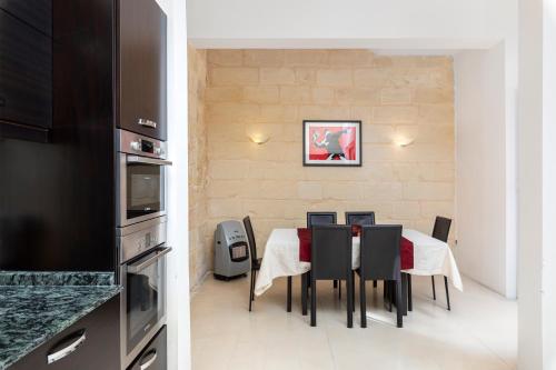 a dining room with a table and chairs in a kitchen at Traditional & Modern Maltese Townhouse - Rooftop Terrace and Sea Views, close to Birgu Waterfront in Cospicua