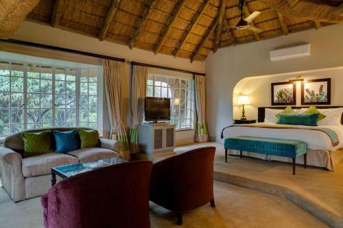 a bedroom with a bed and a couch and a tv at Mount Grace Hotel & Spa in Magaliesburg