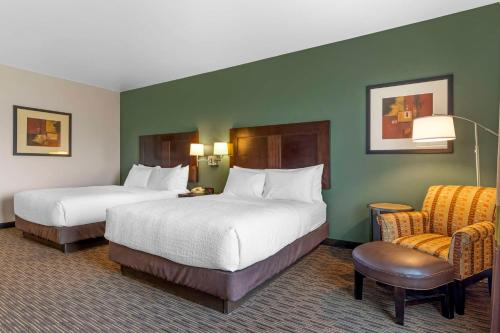 a hotel room with two beds and a chair at Best Western Plus Duncanville/Dallas in Duncanville