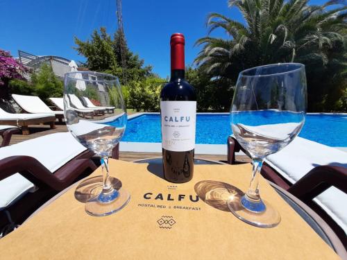 a bottle of wine and two wine glasses on a table at Casa Calfu in Santa Cruz