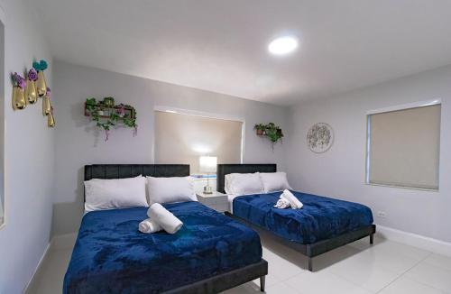 two beds in a bedroom with blue sheets and white pillows at Cool Villa Northwest Miami BY THE GLAMHOMES in Miami