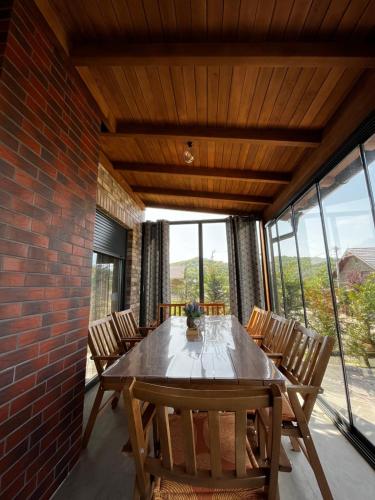 una sala da pranzo con tavolo, sedie e muro di mattoni di Villa Peisazhi a Ferizaj