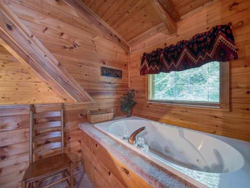 baño con bañera en una cabaña de madera en Bear's Den, 2 Bedrooms, Jetted Tub, King Beds, Hot Tub, WiFi, Sleeps 6, en Gatlinburg