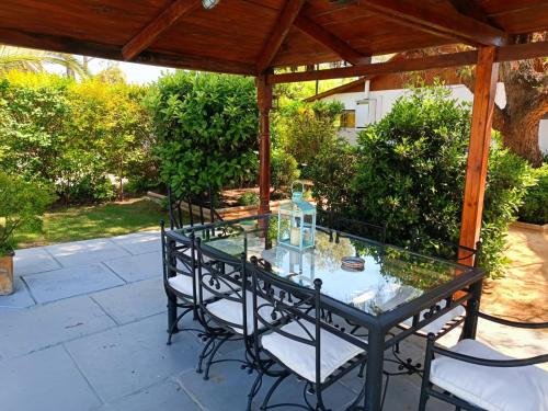 a glass table and chairs under a wooden pergola at Casa Calfu in Santa Cruz