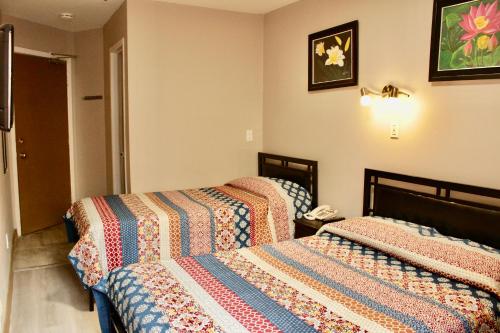 - une chambre avec 2 lits et un téléphone sur le mur dans l'établissement Hotel Victor, à Montréal