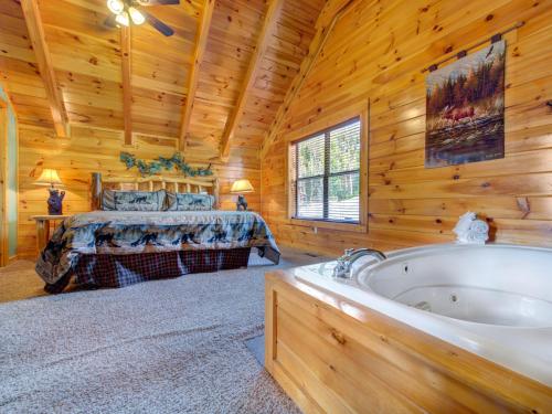 uma cabina de madeira com uma cama e uma banheira em Destiny's Heavenly View, 5 Bedrooms, Sleeps 16, Pet Friendly, Hot Tub, Pool Table em Gatlinburg