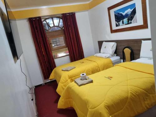 two beds in a room with yellow sheets at Hotel Valery II in Huaraz