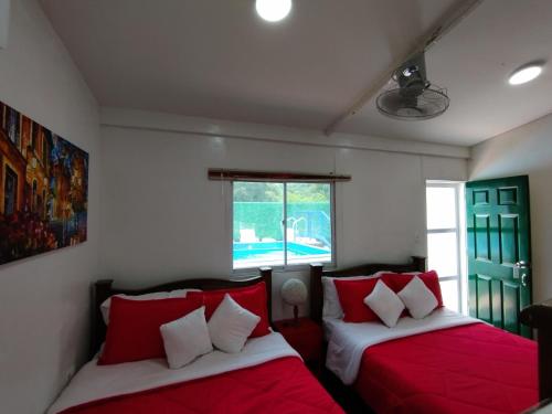 ミンカにあるHostal Paraiso Mincaのベッドルーム1室(ベッド2台、赤と白の枕付)