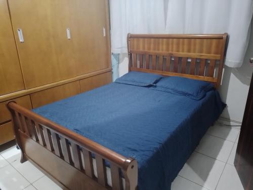 a bedroom with a wooden bed with blue sheets at CANTINHO VOLTE SEMPRE in Aparecida
