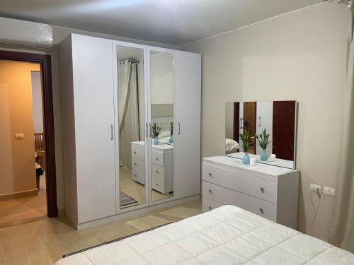 a bedroom with white furniture and a large mirror at قرية أزها العين السخنه in Ain Sokhna