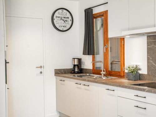 a kitchen with white cabinets and a clock on the wall at Lac Bleu 16 in Lacapelle-Marival