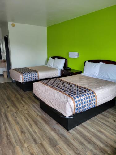 twee bedden in een kamer met een groene muur bij Zainee Inc Budgetel Inn and Suites in Augusta