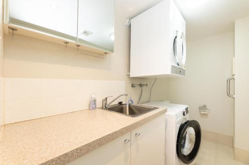 una cocina con fregadero y lavadora en Beachside 2, en Tuncurry