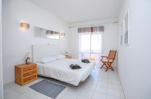 um quarto branco com uma cama e uma cadeira em Lodge Guesthouse em Lagos