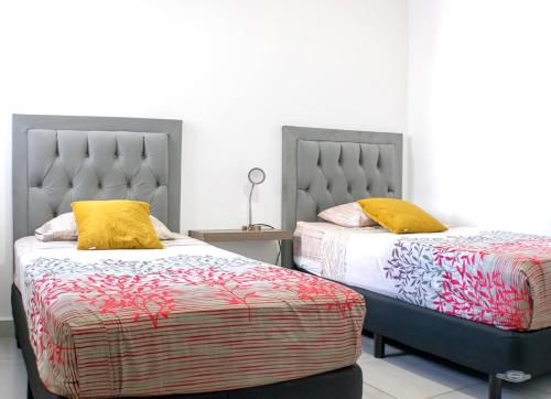 two beds with yellow pillows in a bedroom at Departamento El Marino in Mazatlán