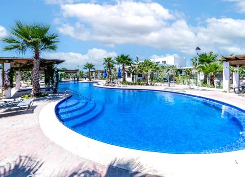 a large swimming pool with palm trees in a resort at Departamento El Marino in Mazatlán