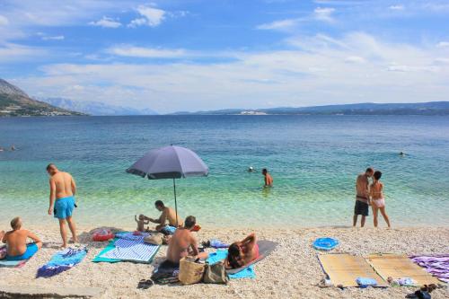 a group of people on a beach with an umbrella at Apartments by the sea Dugi Rat, Omis - 21074 in Dugi Rat