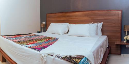 um quarto com uma cama grande e uma cabeceira em madeira em Ahomé Guest house & Lounge em Lomé