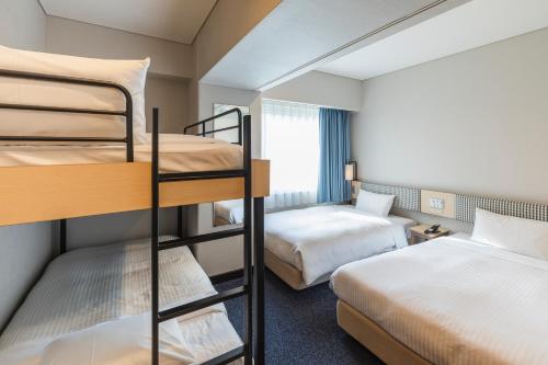 a hotel room with two bunk beds and a bedroom at Sotetsu Fresa Inn Tokyo-Toyocho in Tokyo