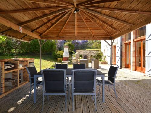 patio con tavolo e sedie sotto un tetto in legno di Charming holiday home with pool a Lavercantière