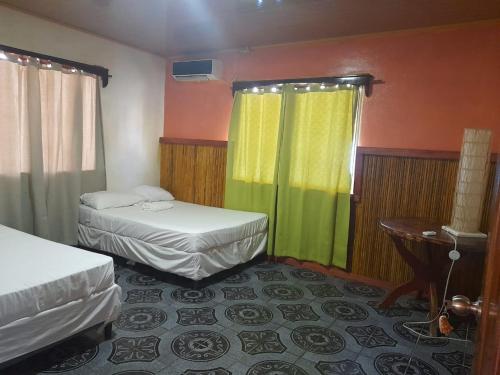 um quarto de hotel com duas camas e uma mesa e cortinas em Hotel Little Queen Lobster em Laguna de Perlas