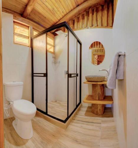 a bathroom with a toilet and a glass shower at Sámara Tarantela Houses, Casa Sandal in Sámara