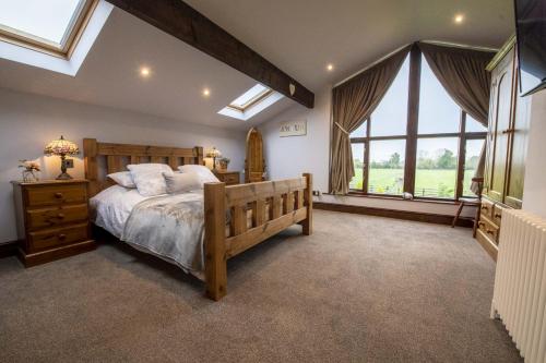 Schlafzimmer mit einem großen Bett und Fenstern in der Unterkunft Tockwith Lodge Barn in York